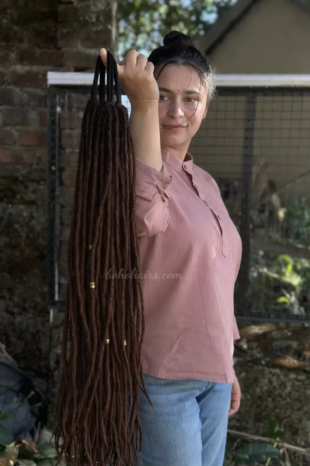 Woman holding a bundle of long braids outdoors