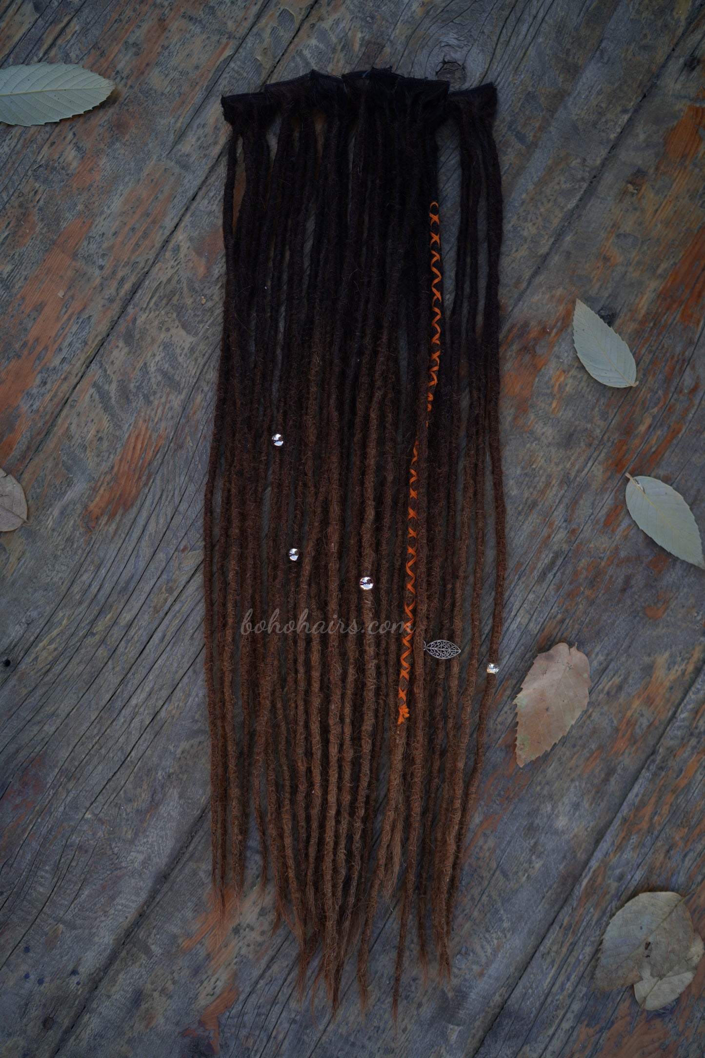 Braided hair extensions on a wooden surface with leaves