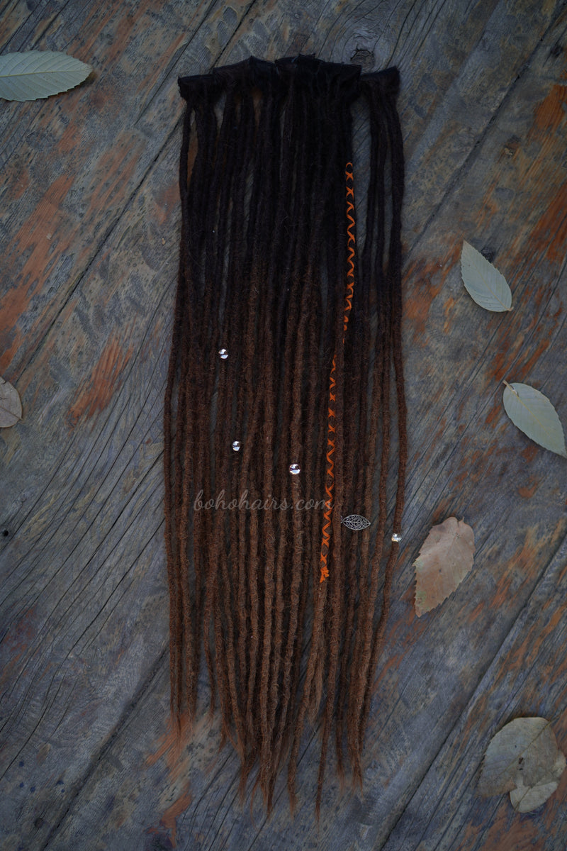 Braided hair extensions on a wooden surface with leaves